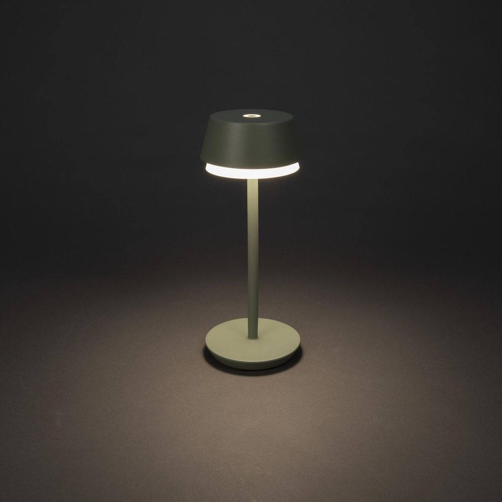 Eine grüne Lampe mit rundem Fuß und Schirm, die sanft leuchtet.