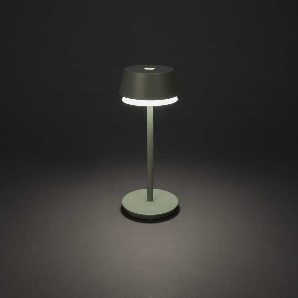 Eine grüne Tischlampe mit rundem Fuß und kegelförmigem Schirm, die Licht spendet.