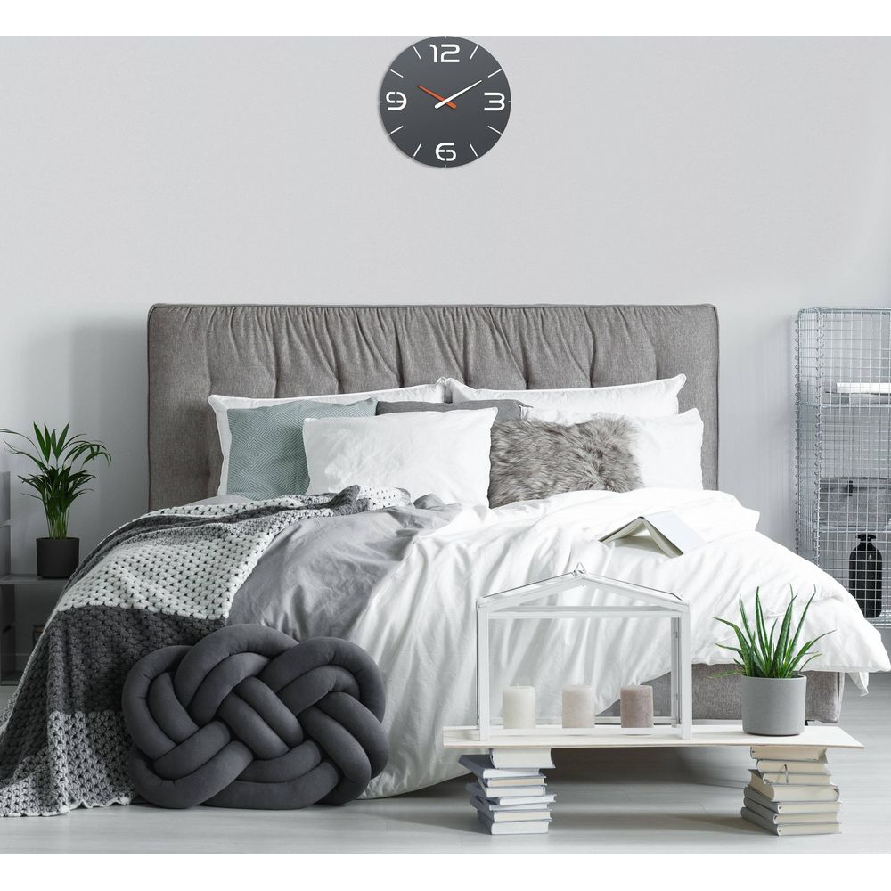 Modernes Schlafzimmer mit weißer Bettwäsche, grauen Kissen und einer Wanduhr.
