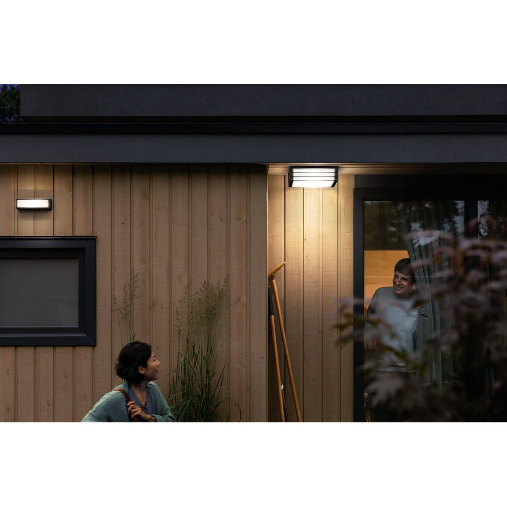 Hombre y mujer frente a una casa de madera con luz exterior.