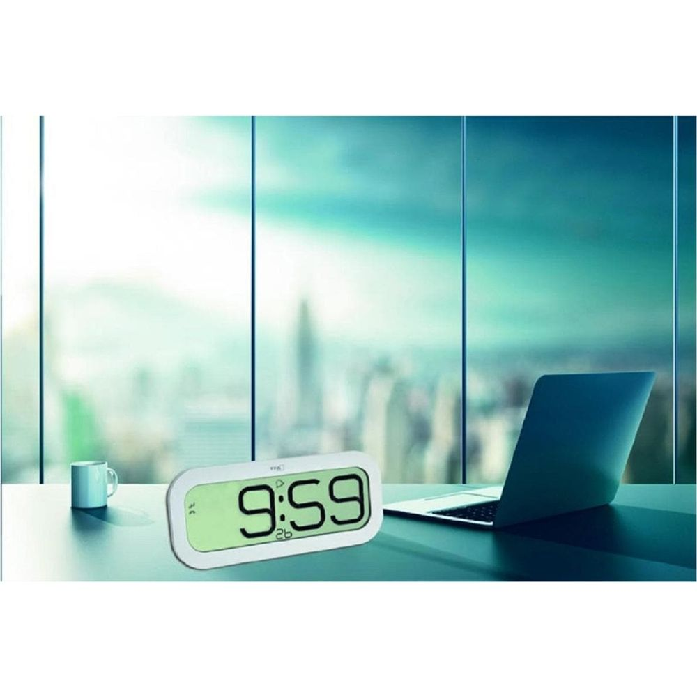 Digitaluhr zeigt 9:59 neben Laptop und Tasse, mit Stadtblick.