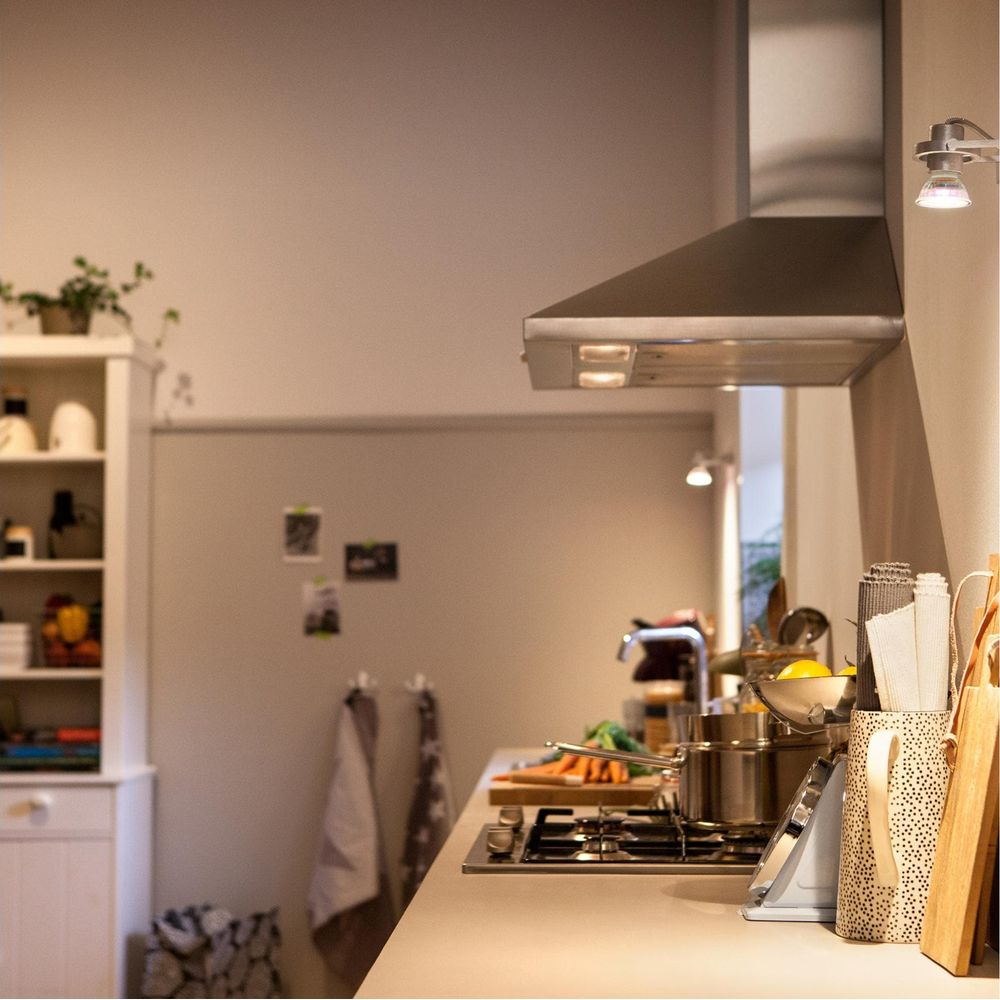 Een keuken met afzuigkap, fornuis, potten en groenten.