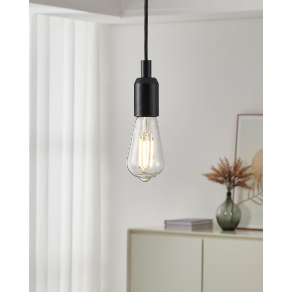 Une ampoule transparente avec douille noire pend du plafond.