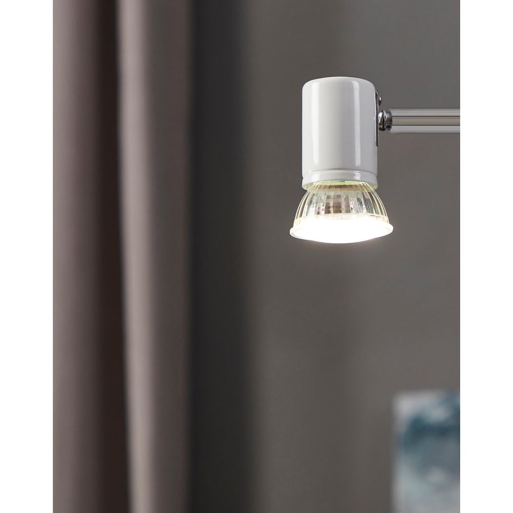 Une lampe blanche avec diffuseur en verre et bras chromé brille.