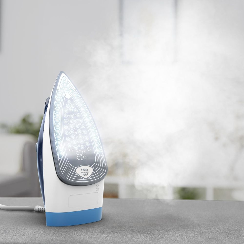 Un fer à repasser à vapeur avec des accents bleus et blancs émet de la vapeur.