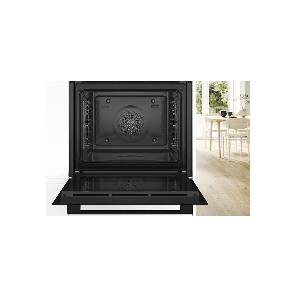 Nowoczesny piekarnik do zabudowy z otwartymi drzwiami, widok wnętrza i jadalnia w tle.