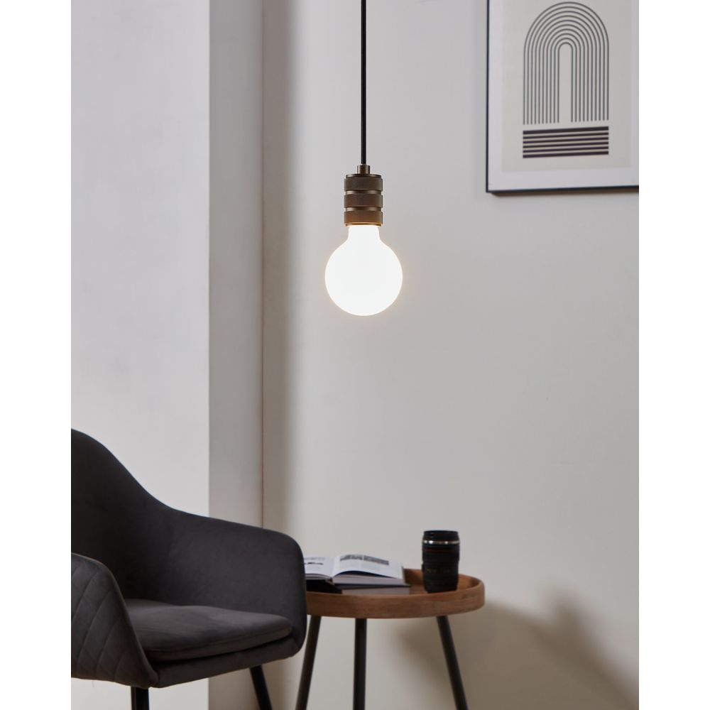 Une suspension avec ampoule au-dessus d'un fauteuil et d'une table d'appoint.