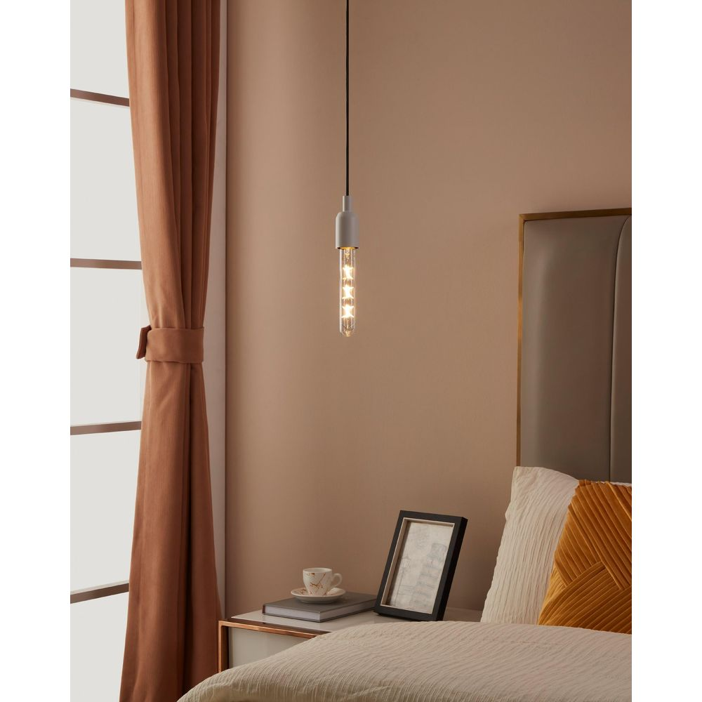 Un comodino con lampada, quadro e tazza accanto a un letto.