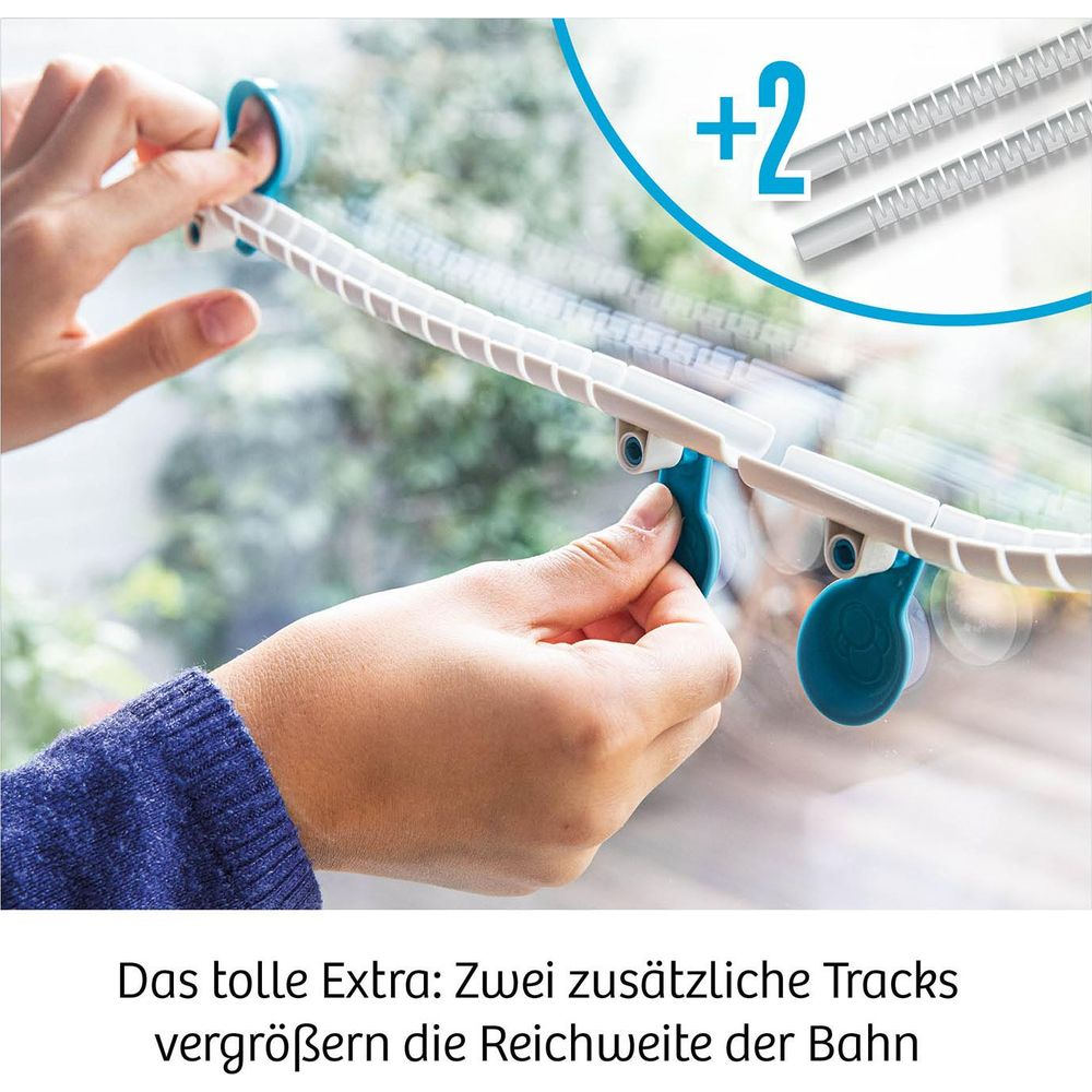 Hände befestigen weiße Schiene mit blauen Clips an Fenster. Zusätzliche Teile sichtbar.