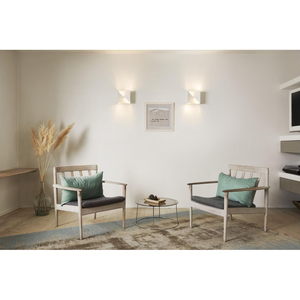 Deux fauteuils avec coussins verts, table basse, vase avec roseaux, tableaux, appliques.