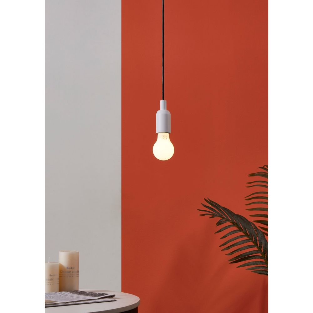 Une suspension blanche avec une ampoule pend devant un mur orange.