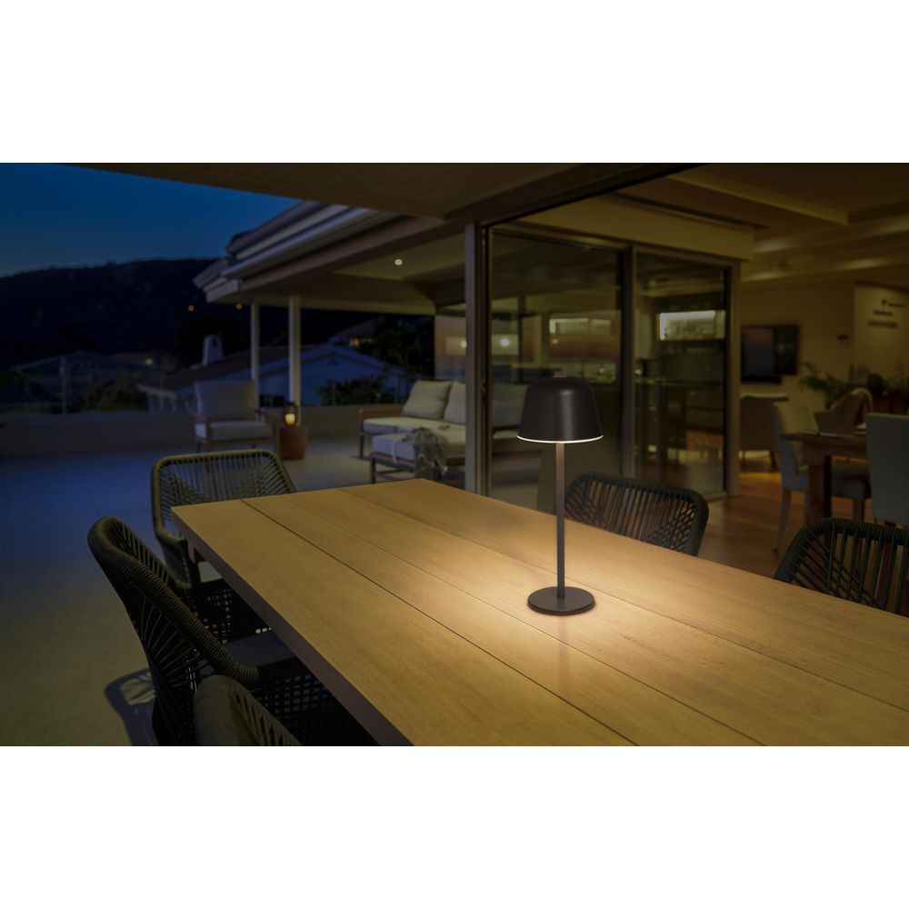 Una lampada scura su un tavolo di legno su un portico di notte.