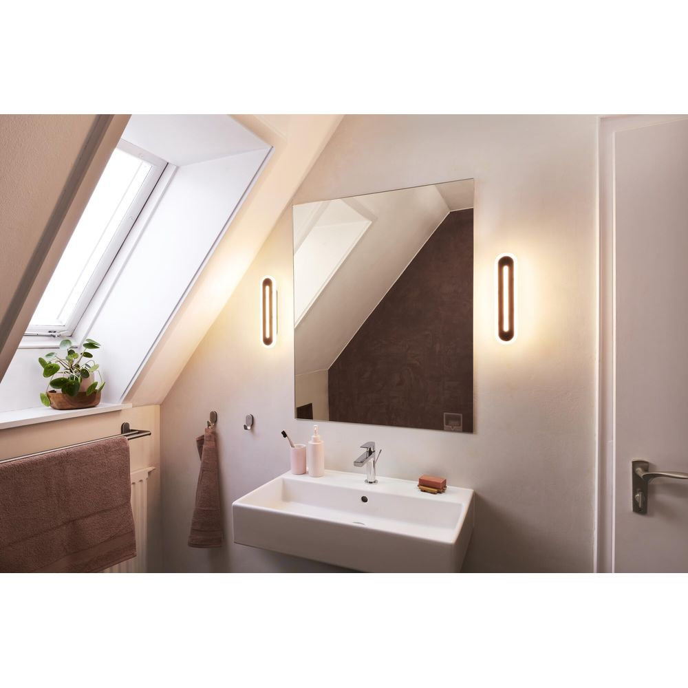 Modernes Badezimmer mit Waschbecken, Spiegel, Fenster und Wandleuchten.