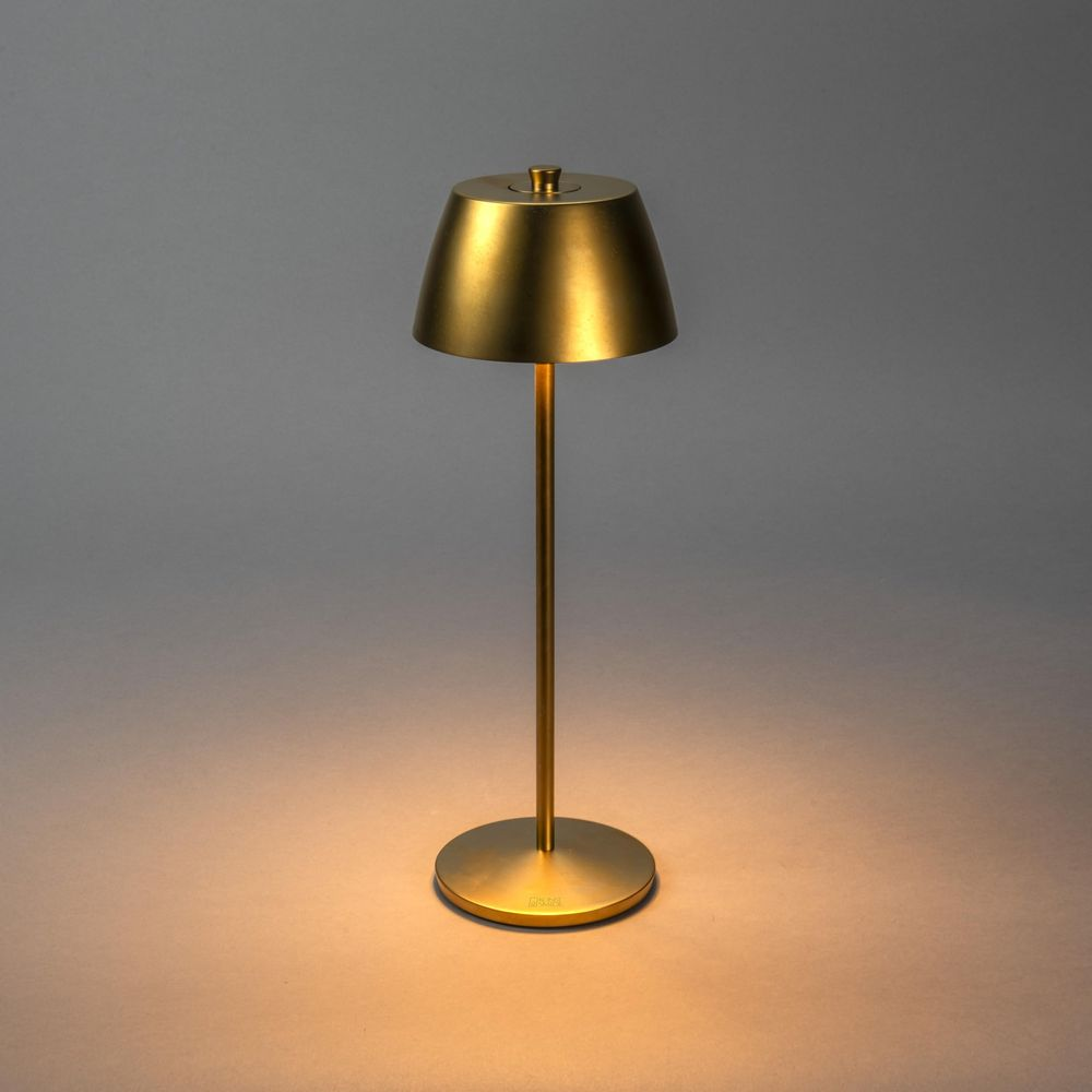 Goldene Tischlampe mit rundem Sockel und kegelförmigem Schirm. Leuchtet warm.