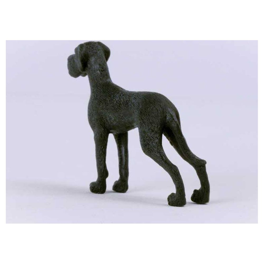 Ciemny, krótko sierściowy posąg psa, stojący bokiem na białym tle.