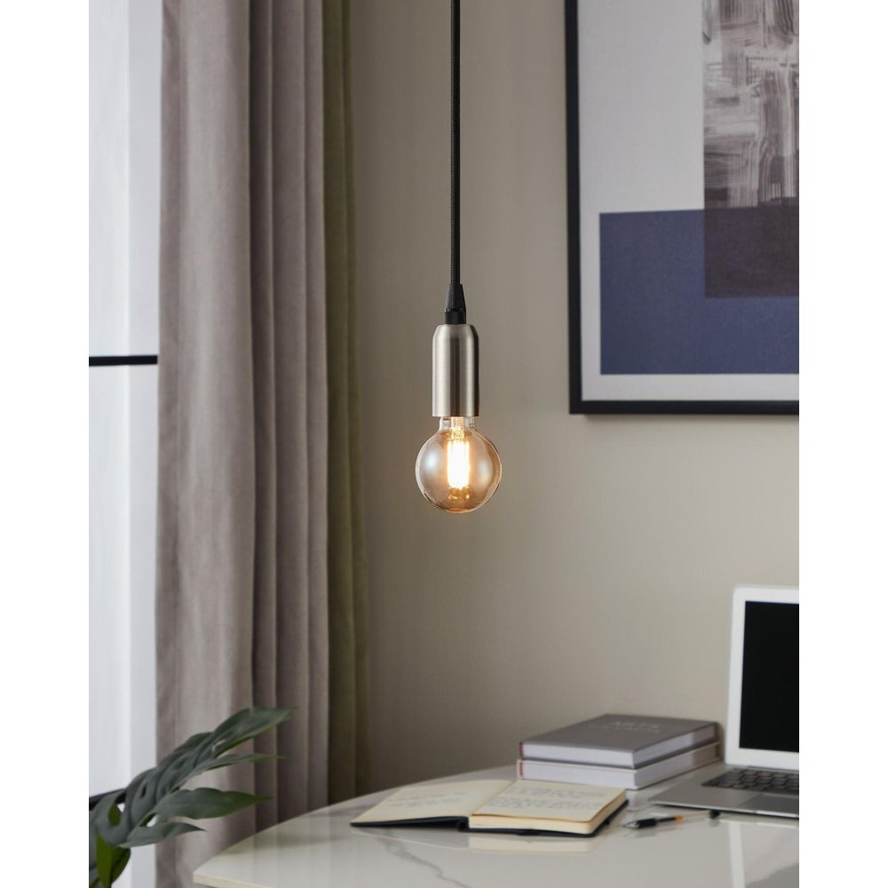 Une suspension avec une ampoule vintage suspendue au-dessus d'un bureau avec un ordinateur portable et des livres.