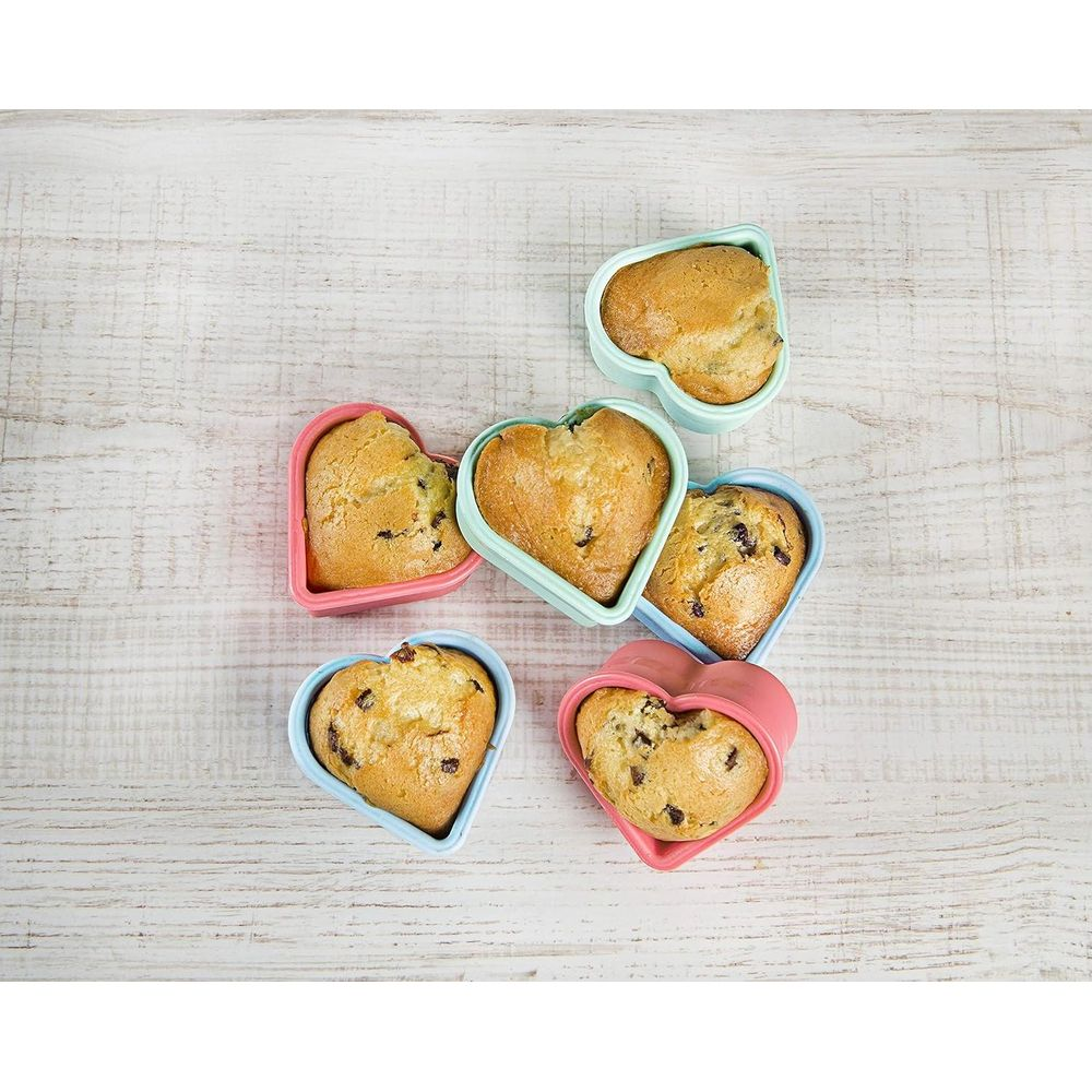 Sechs herzförmige Muffins in bunten Formen auf Holzhintergrund.