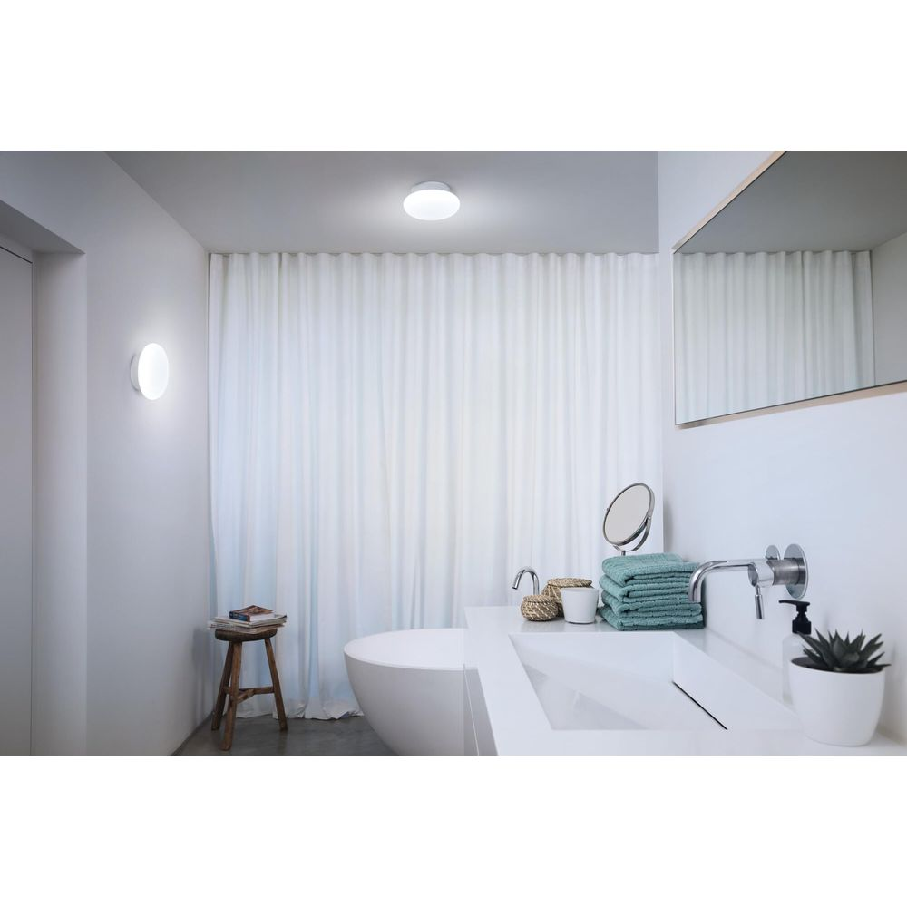 Bagno moderno con vasca freestanding, lavandino e tende bianche.