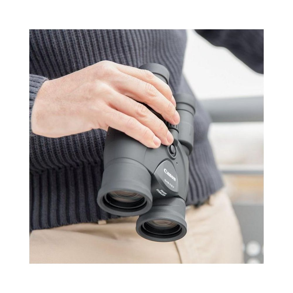 Dłoń trzyma szare lornetkę Canon z stabilizacją obrazu.