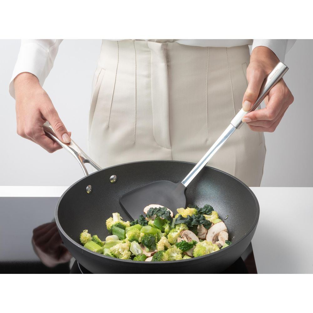 Una persona cucina broccoli, funghi e cavolfiore in un wok.