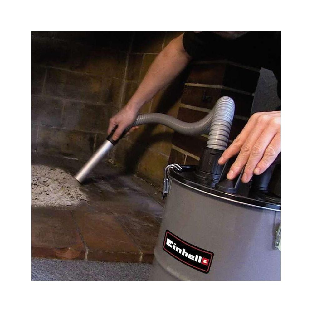 Person saugt Asche mit einem Staubsauger aus einem Kamin.