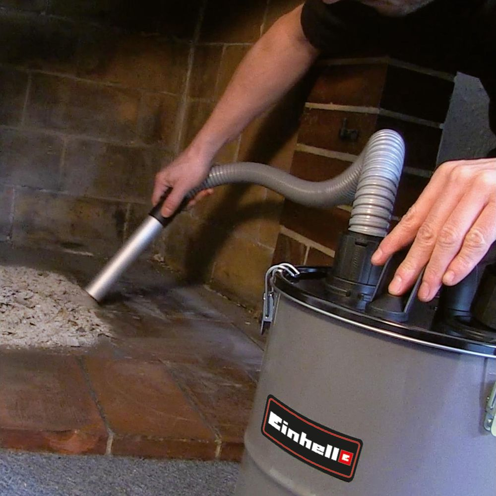 Mann saugt Asche aus einem Kamin mit einem Einhell-Aschesauger.