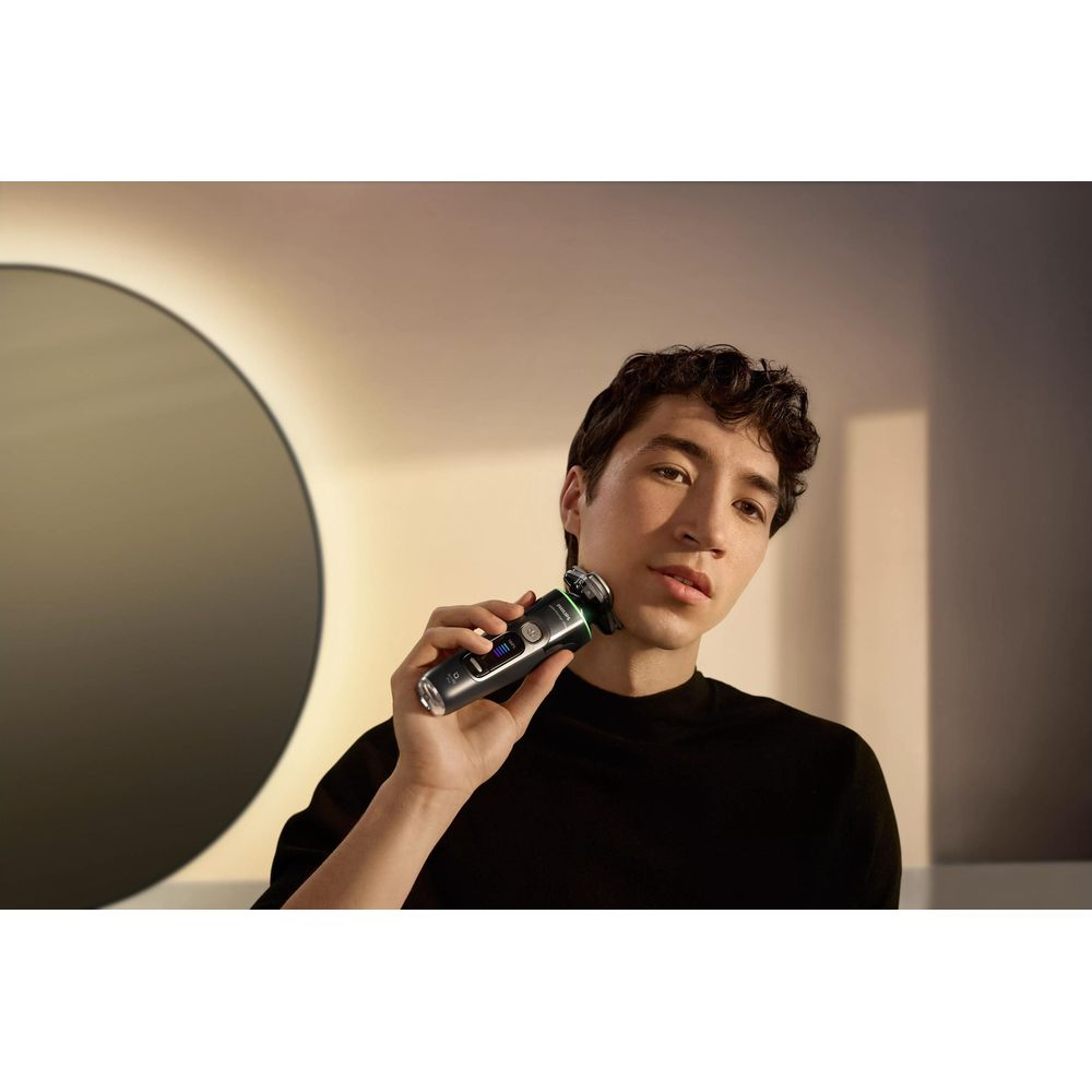 Mężczyzna goli twarz golarką elektryczną.