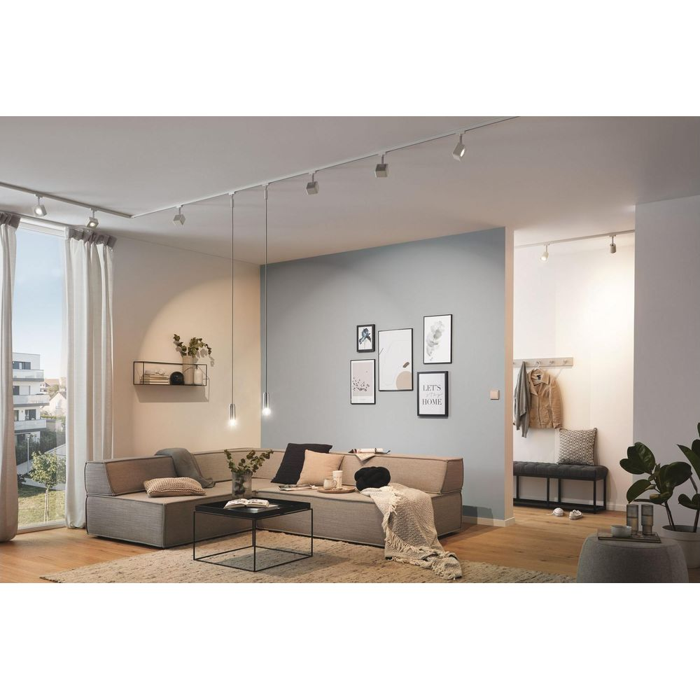 Ein helles Wohnzimmer mit Ecksofa, Couchtisch, Wandkunst und Garderobe.