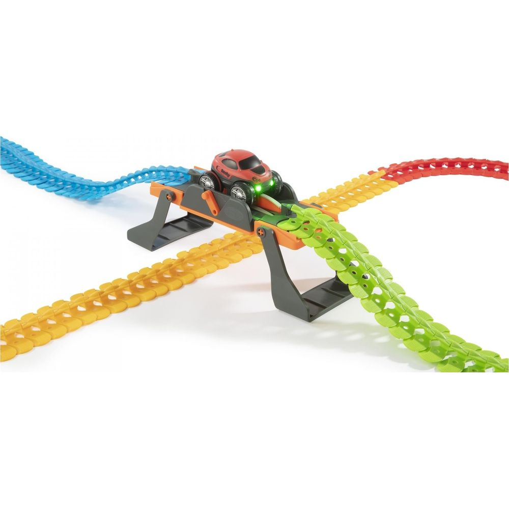 Czerwony samochodzik jedzie po kolorowym torze z mostkiem i skrzyżowaniem.