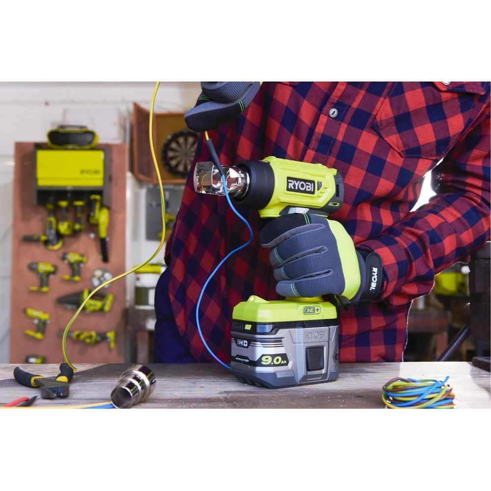 Une personne avec des gants utilise un pistolet thermique jaune alimenté par batterie.