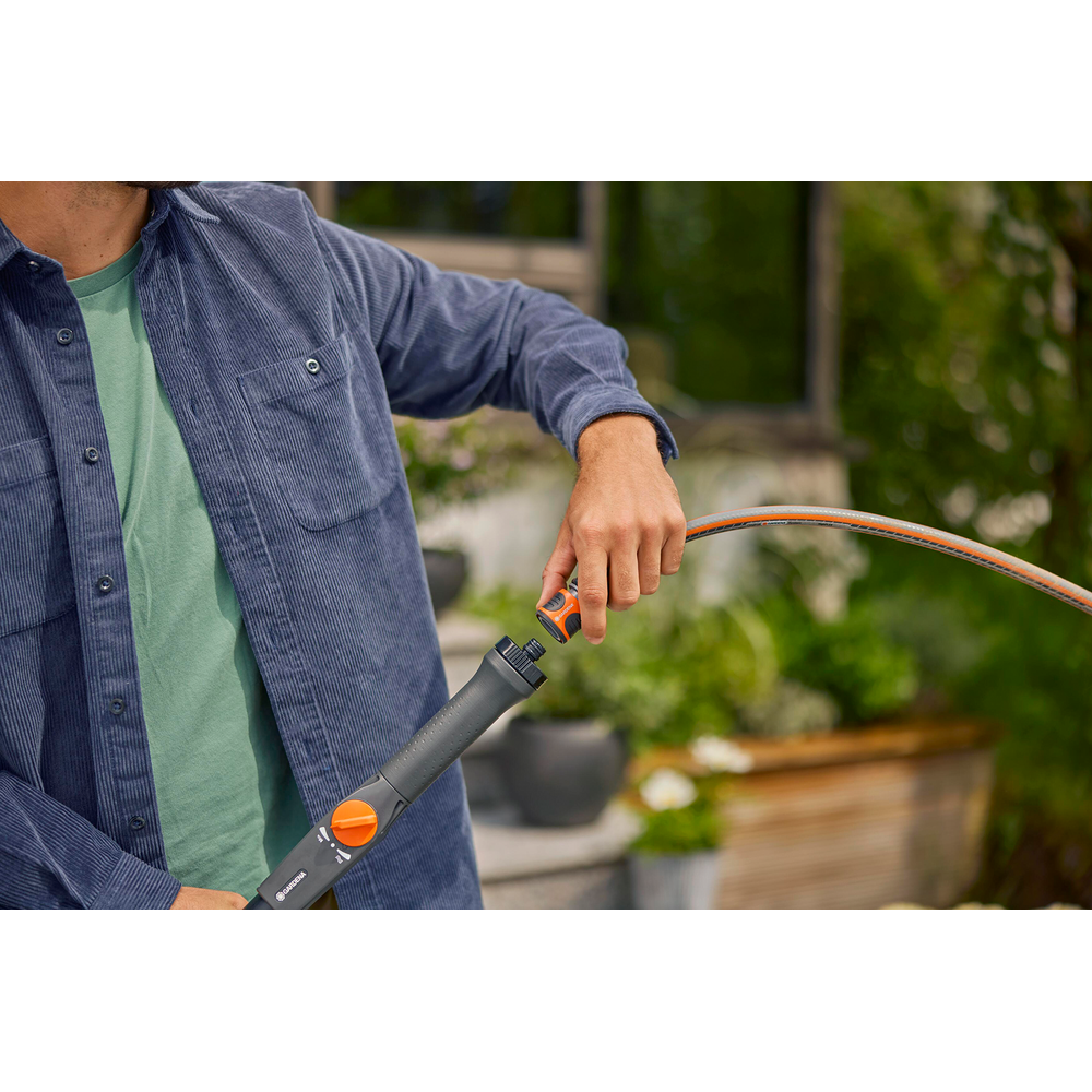 Hombre conecta manguera de jardín a mango de pistola.