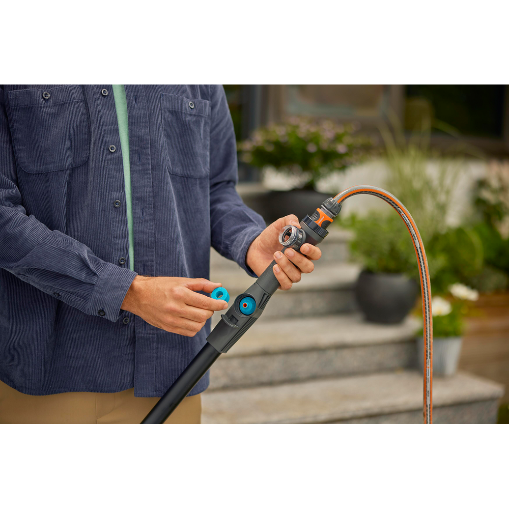 Hombre sujetando un conector de manguera de jardín con pieza azul.