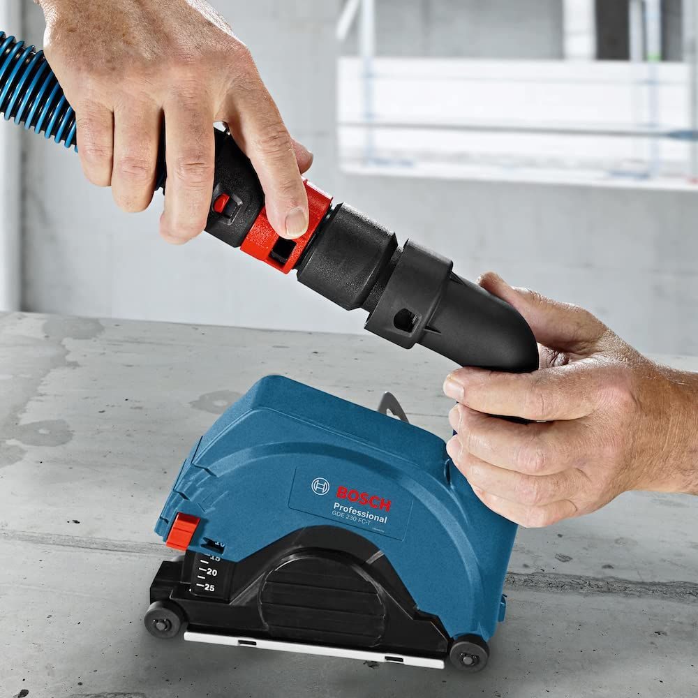 Un uomo attacca un tubo blu a un utensile Bosch blu su una superficie di cemento.
