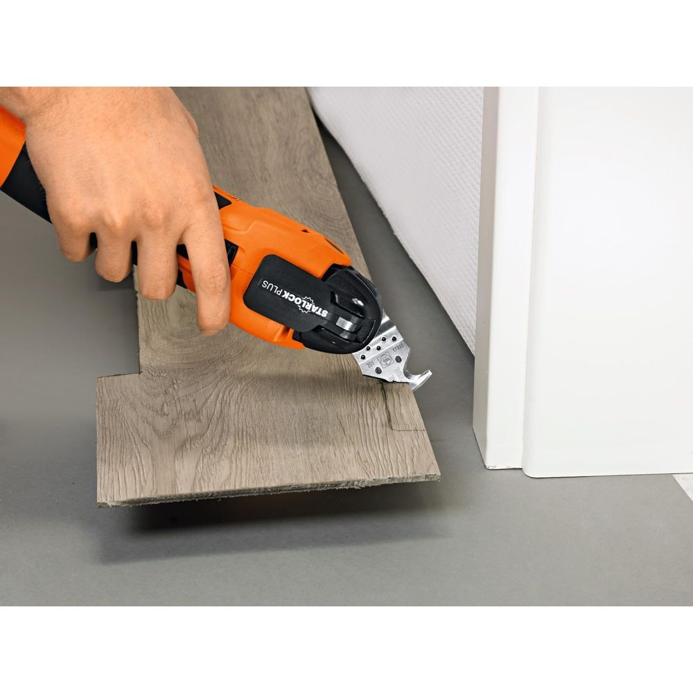 Eine Hand hält ein orangefarbenes Multifunktionswerkzeug, das einen Holzboden schneidet.