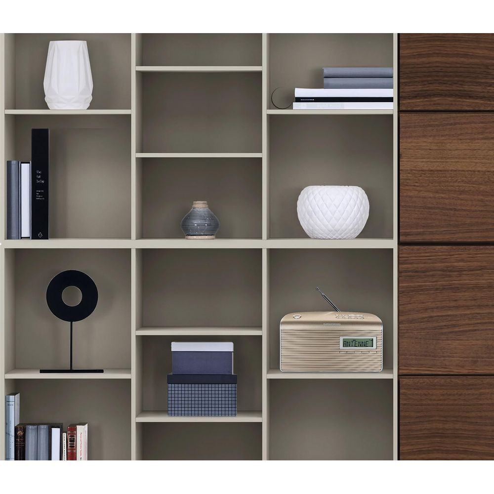 Złote radio z antenką stoi na półce obok dwóch pudełek.