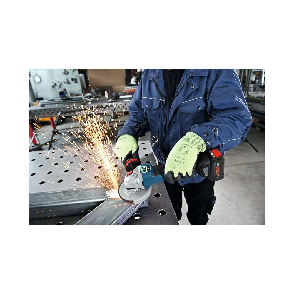 Eine Person in blauer Jacke und grünen Handschuhen benutzt Winkelschleifer an Metall, Funkenflug.