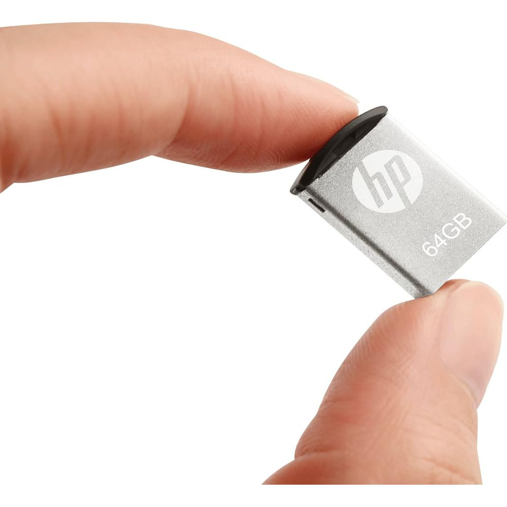 Osoba trzyma srebrny pendrive HP 64 GB między kciukiem a palcem wskazującym.