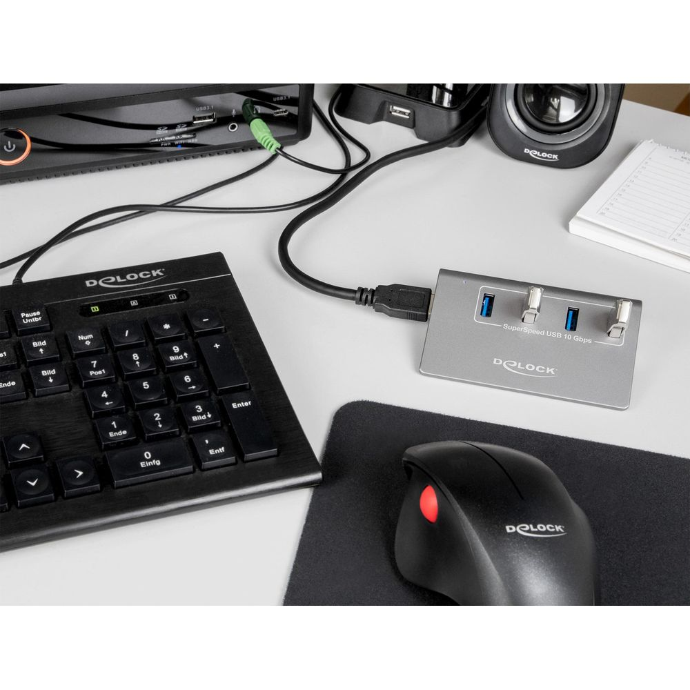 Ein grauer USB-Hub mit drei Anschlüssen steht neben einer schwarzen Tastatur und Maus.