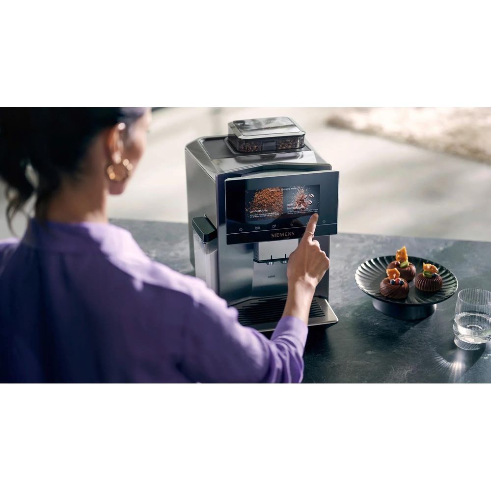 Frau bedient Kaffeemaschine mit Touchscreen. Daneben Schokolade-Desserts.