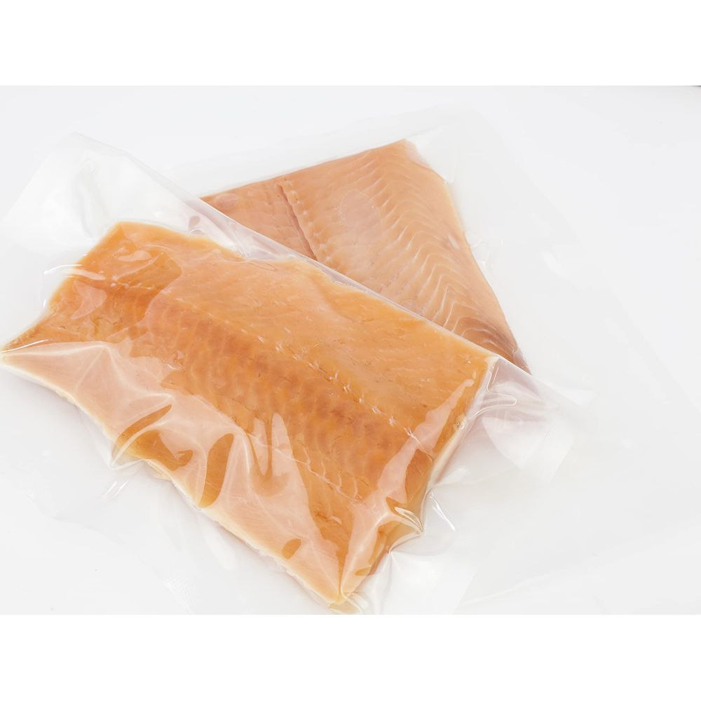 Zwei vakuumverpackte Lachsfilets auf weißem Hintergrund.