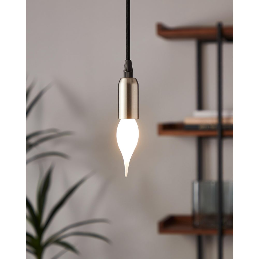 Una lampadina a forma di goccia con attacco in ottone pende da un cavo nero.