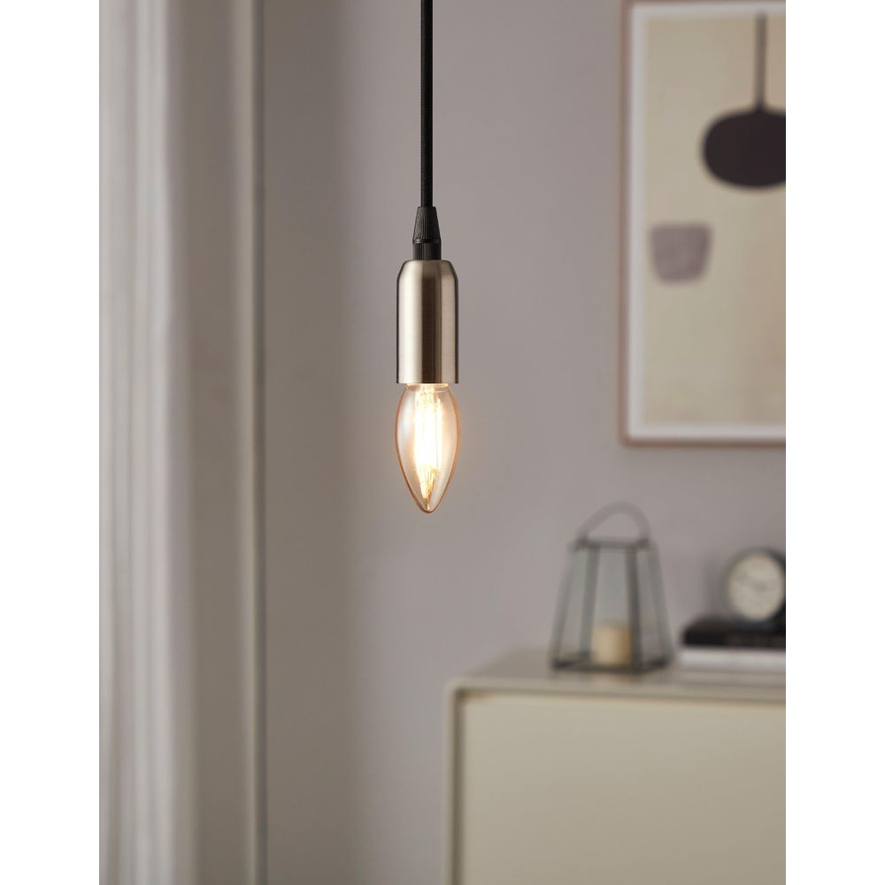 Une ampoule suspendue avec un luminaire en métal au-dessus d'une table de chevet.
