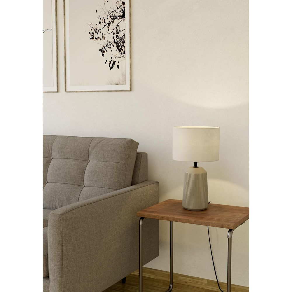 Graues Sofa neben einem Holztisch mit Lampe. Zwei Bilder an der Wand.
