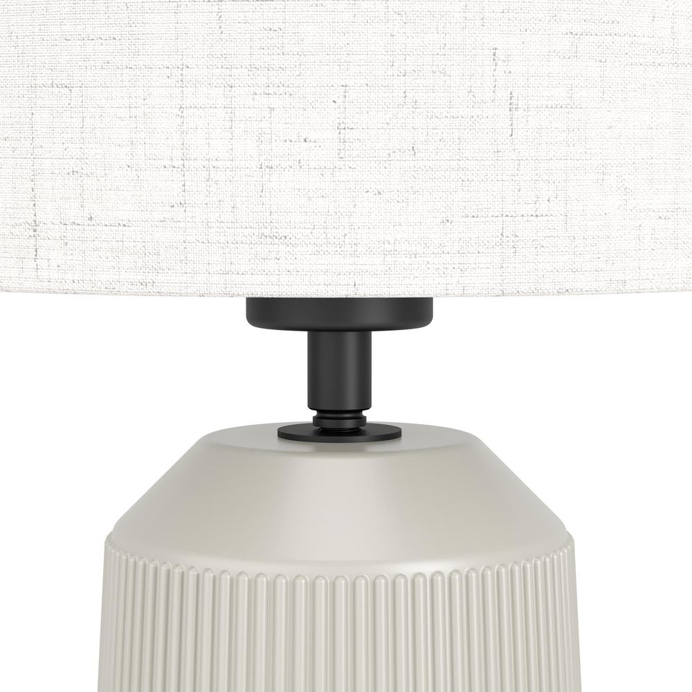 Eine weiße Lampe mit vertikal geripptem Sockel und schwarzem Ständer.