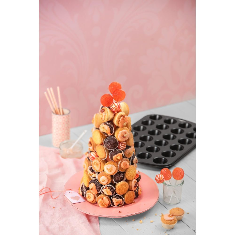 Ein kegelförmiger Kuchen aus Mini-Muffins, verziert mit Lollis, auf einem rosa Teller.