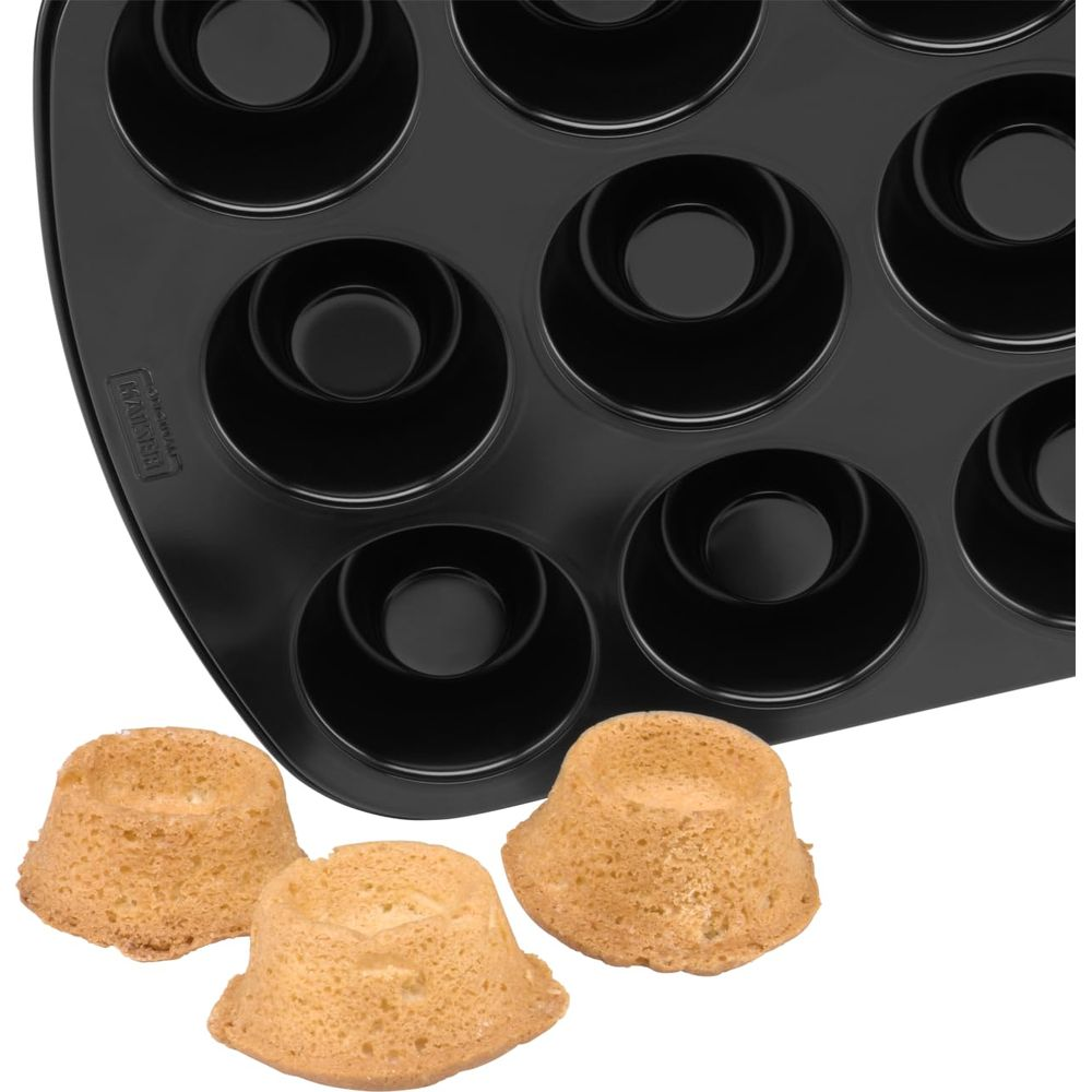 Ein schwarzes Backblech für 12 Donuts mit drei gebackenen Donuts daneben.