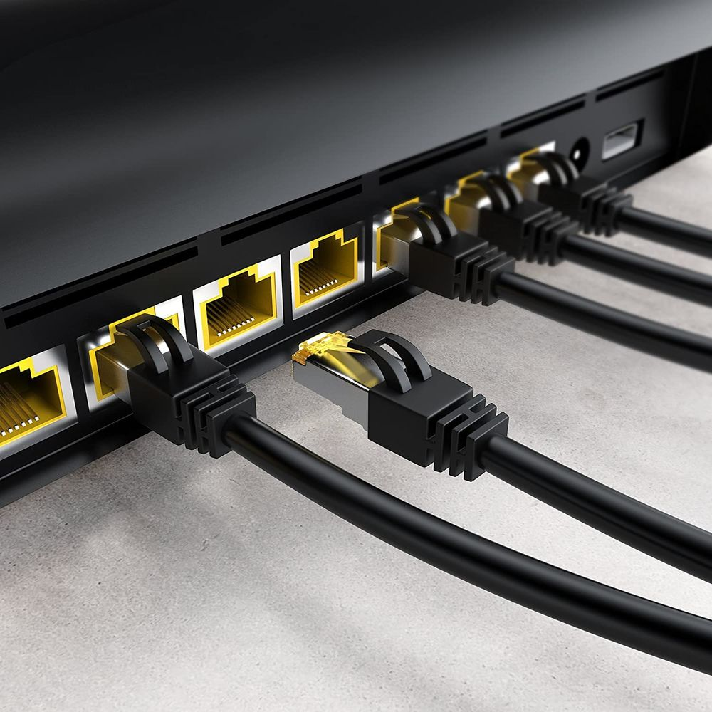Czarne kable Ethernet podłączone do czarnego routera z żółtymi portami.