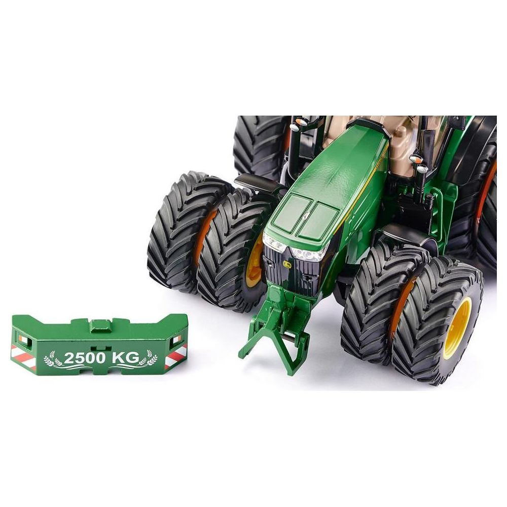 Tractor de juguete verde con peso delantero. Ruedas grandes con llantas amarillas.