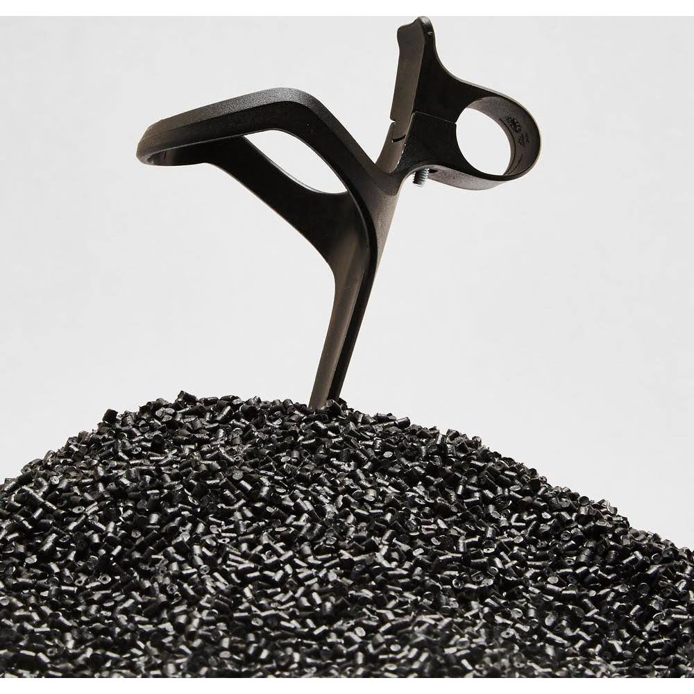 Czarna plastikowa część wyrasta z kupki czarnych granulek.
