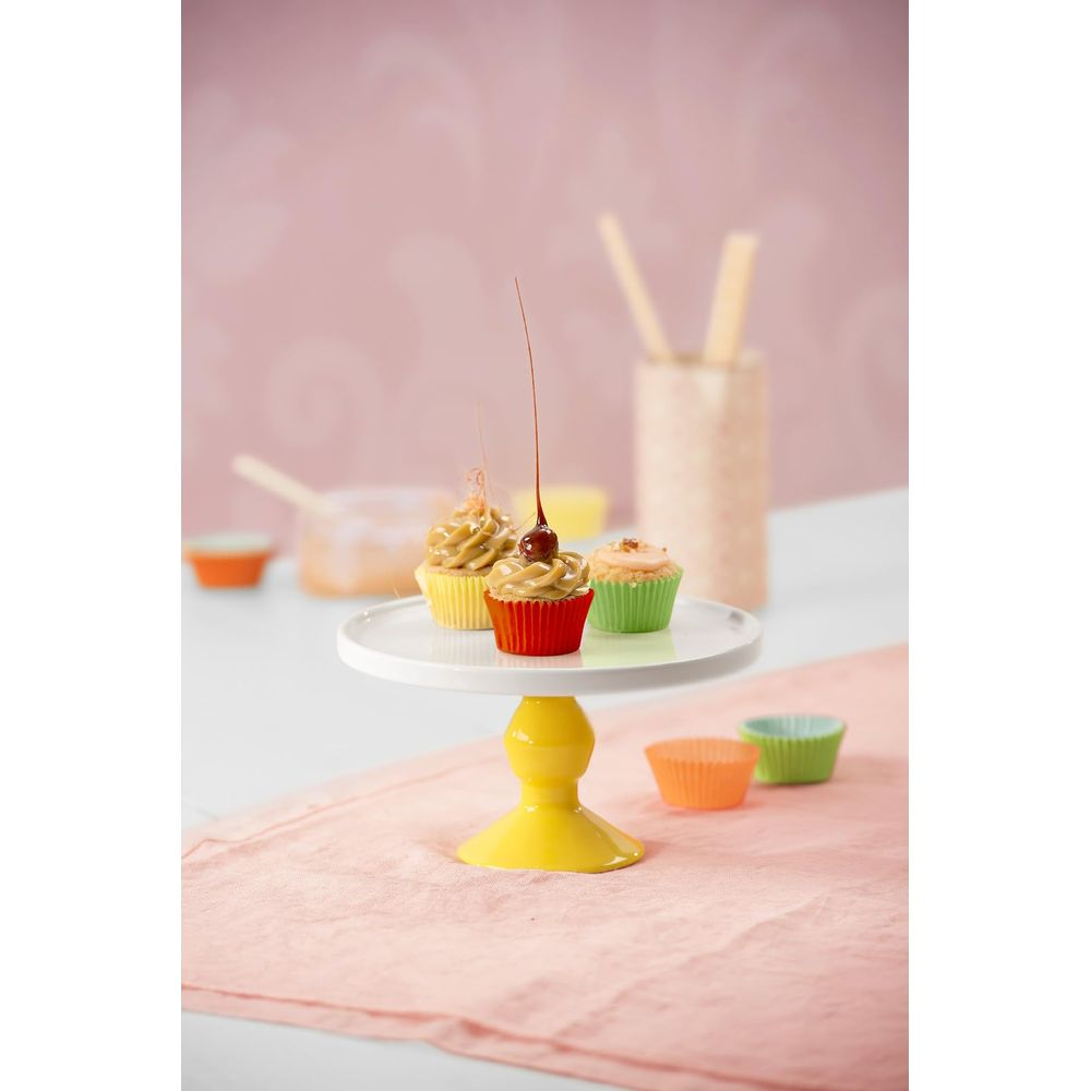 Drei Cupcakes auf einem gelben Ständer, dekoriert mit Karamell und Kirsche.